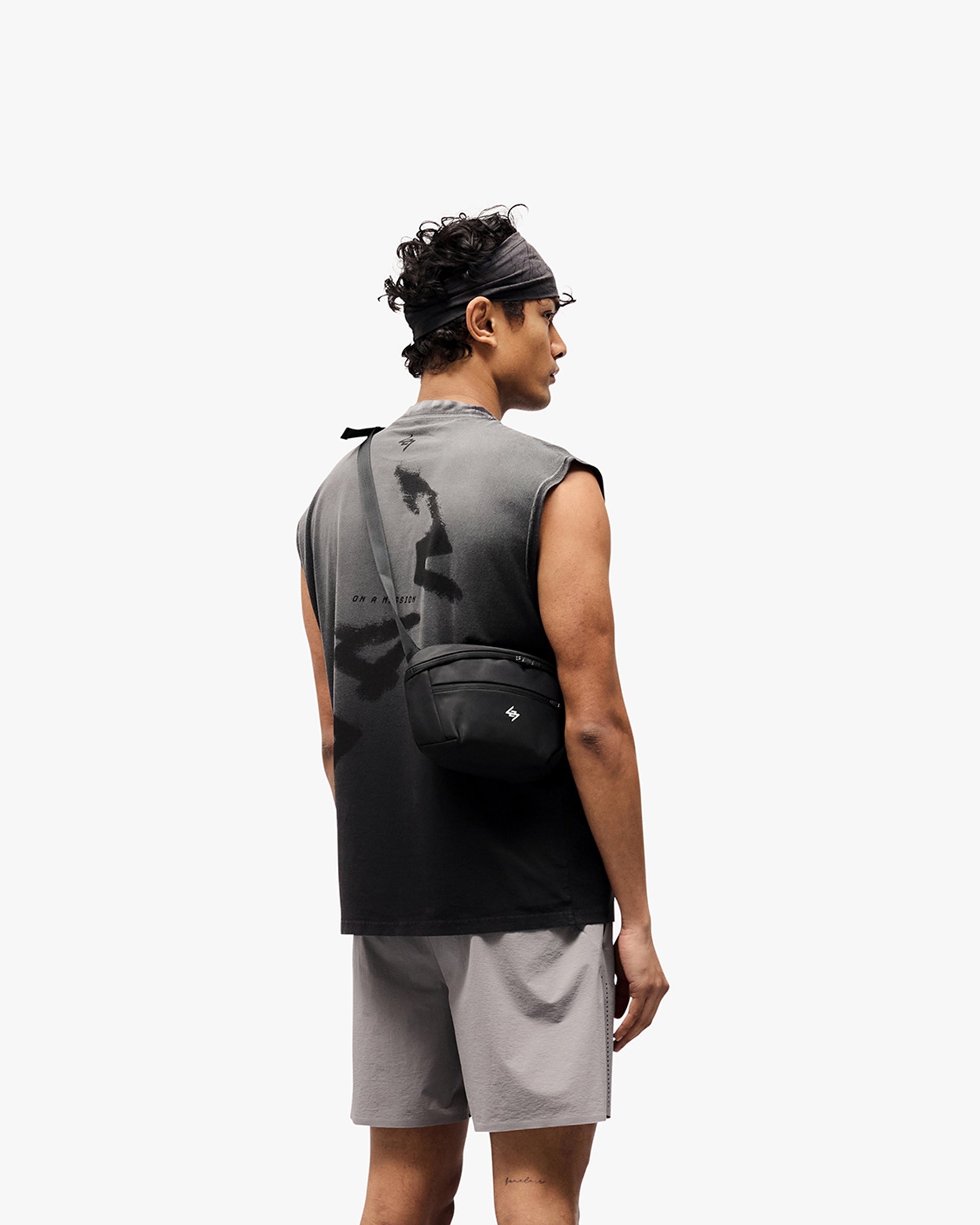 Man wearing a black tank top on a plain white background | 247 Motion Oversized Tank in Aged Black | Oversized tank with water based graphic print | 247 T-Shirts | Represent Clo