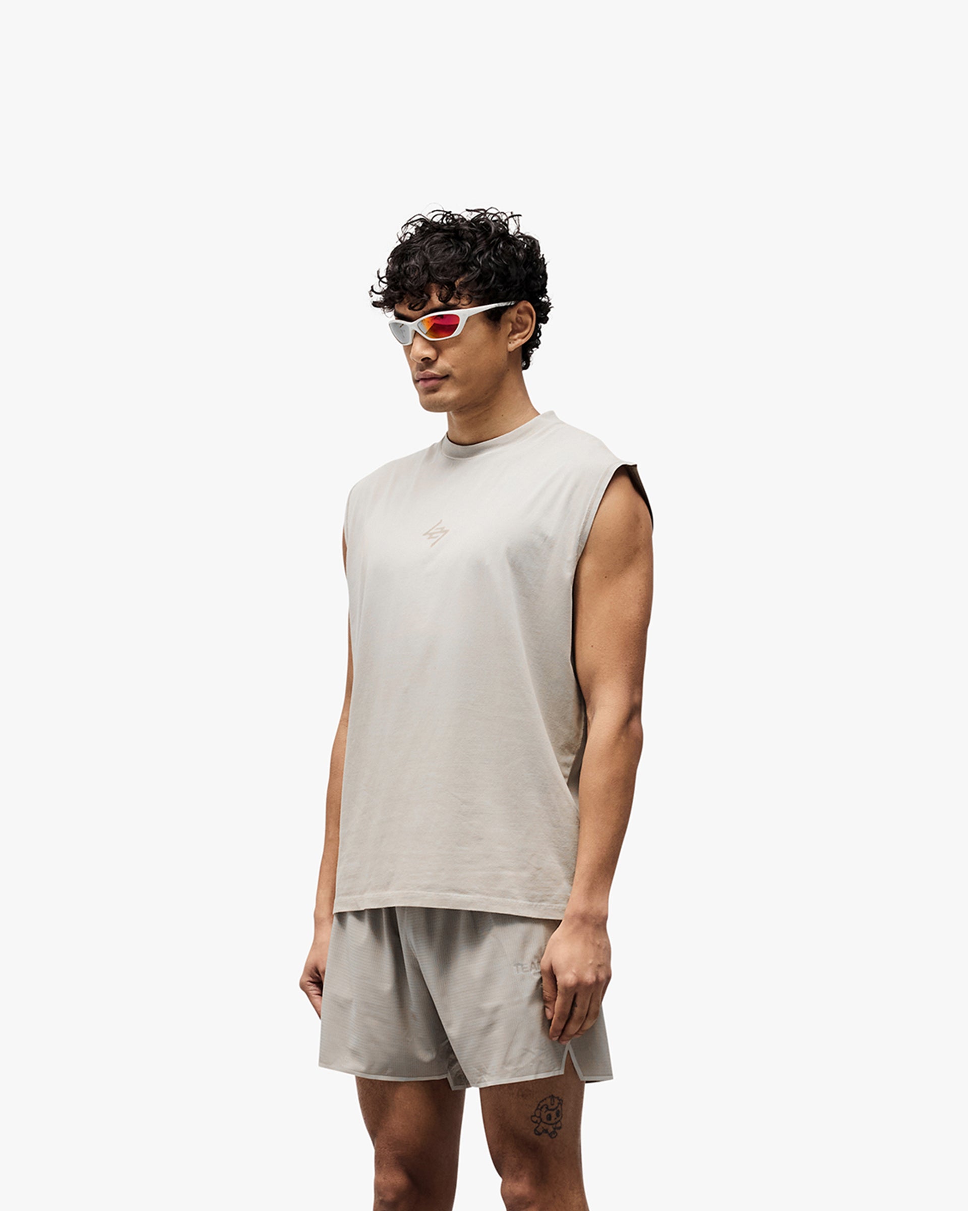 Man wearing a grey oversized tank on a plain white background | 247 Motion Oversized Tank in Pebble | Oversized tank with water based graphic and 2 way stretch | 247 T-Shirts | Represent Clo