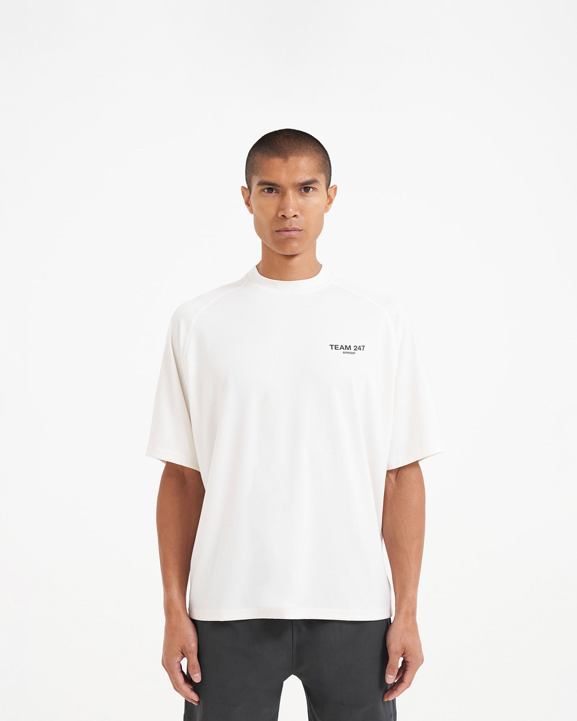 Man wearing an oversized white t-shirt on a plain white background | Team 247 Oversized T-Shirt in Flat White | Lightweight quick-dry gym t-shirt | 247 T-Shirts | Represent Clo
