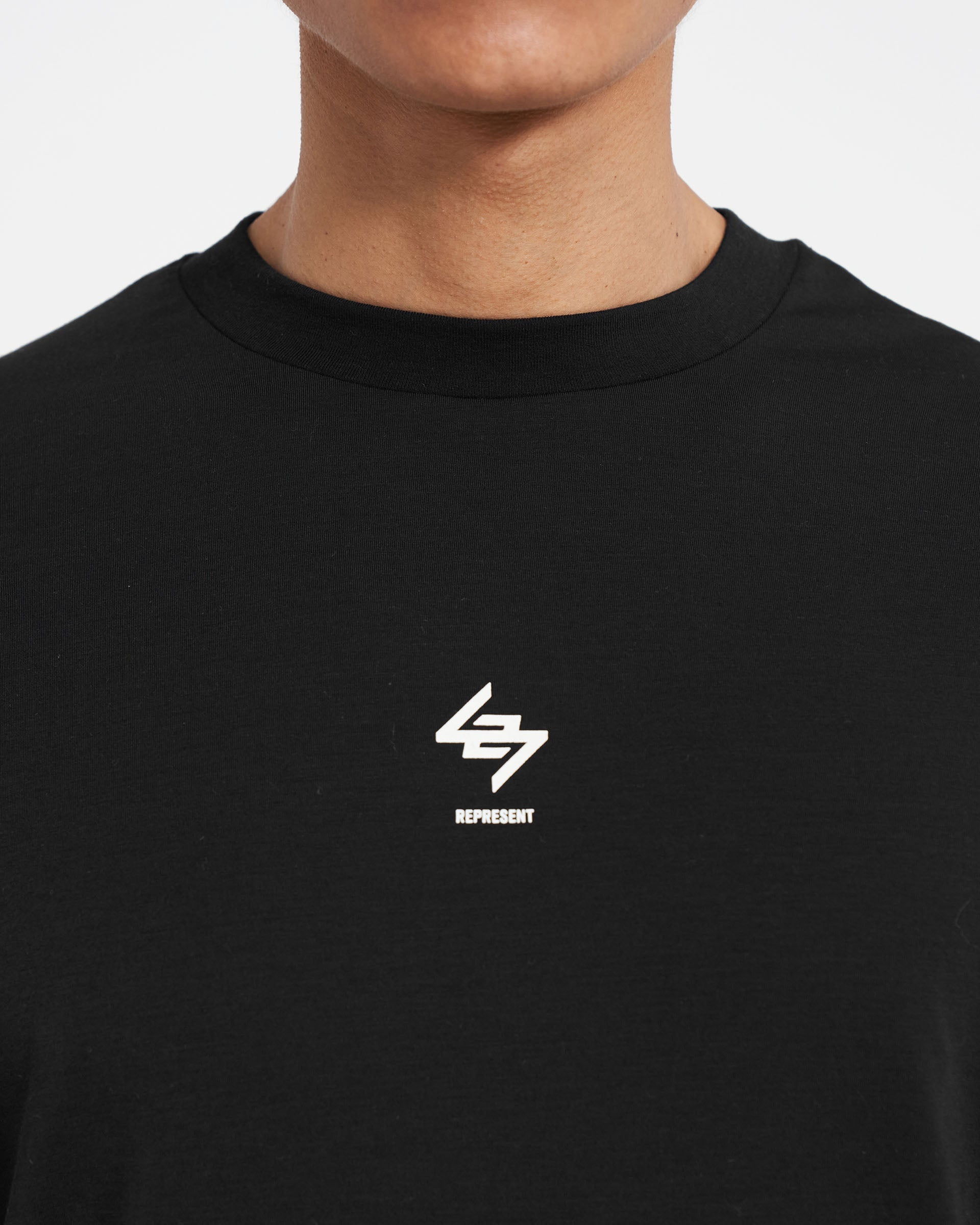 Man wearing a black oversized t-shirt on a plain white background | 247 Oversized T-Shirt in Jet Black | Breathable and quick dry gym top | 247 T-Shirts | Represent Clo