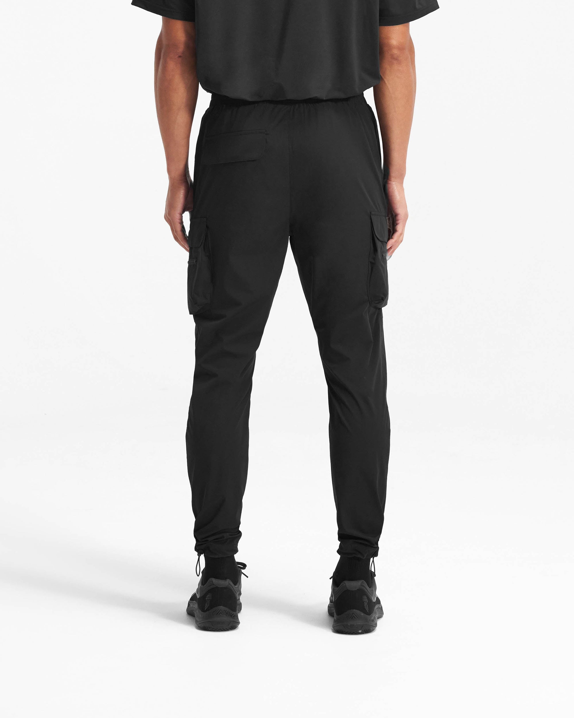 Man wearing black pants on a plain white background | 247 Pant in Black | Versatile cargo pants with technical 4-way stretch and cargo pockets | 247 Pants | Represent Clo