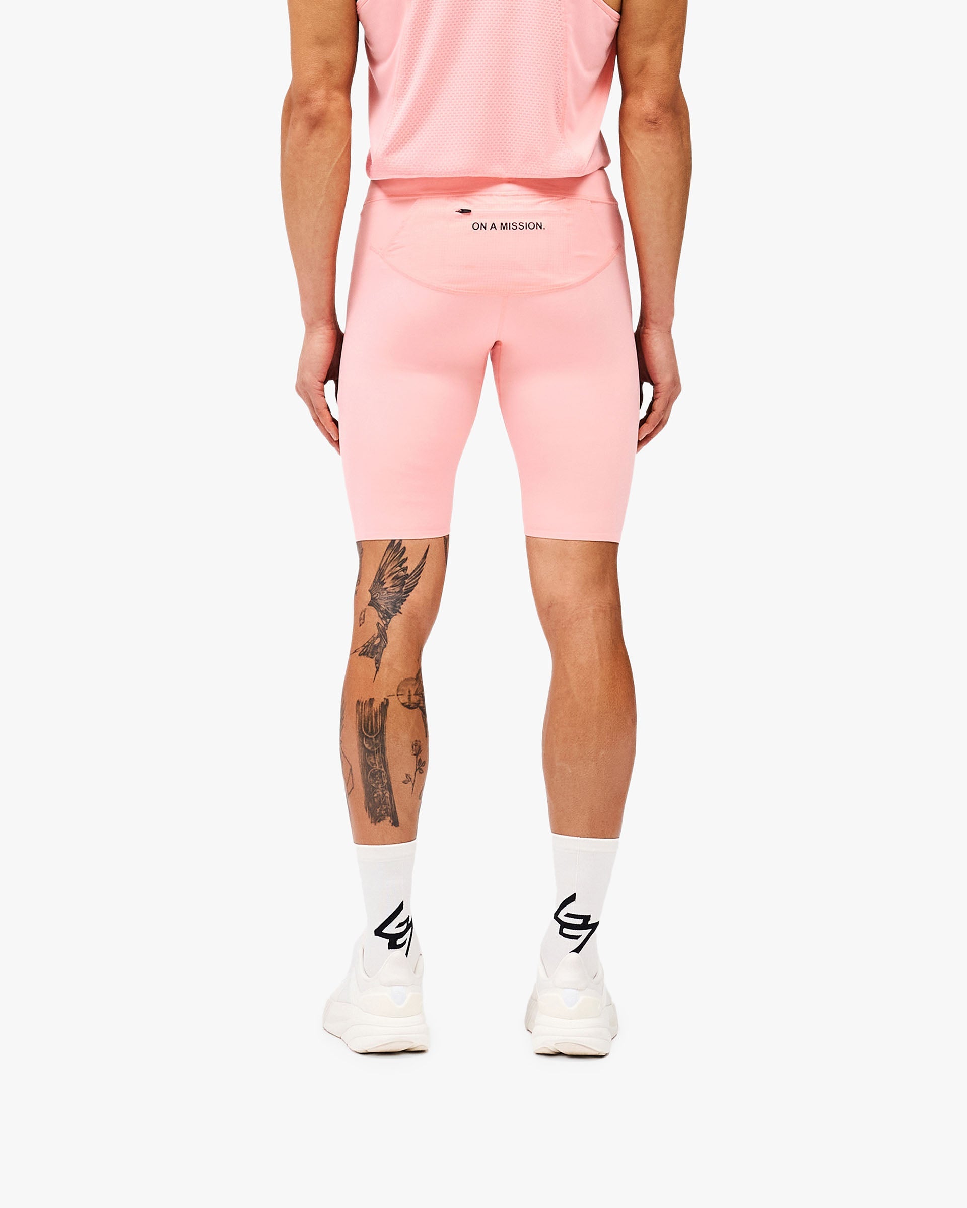 Man wearing pink compression shorts on a plain white background | 247 Los Angeles Half Tight in Pink | Performance shorts with secure zip pocket | 247 Shorts | Represent Clo