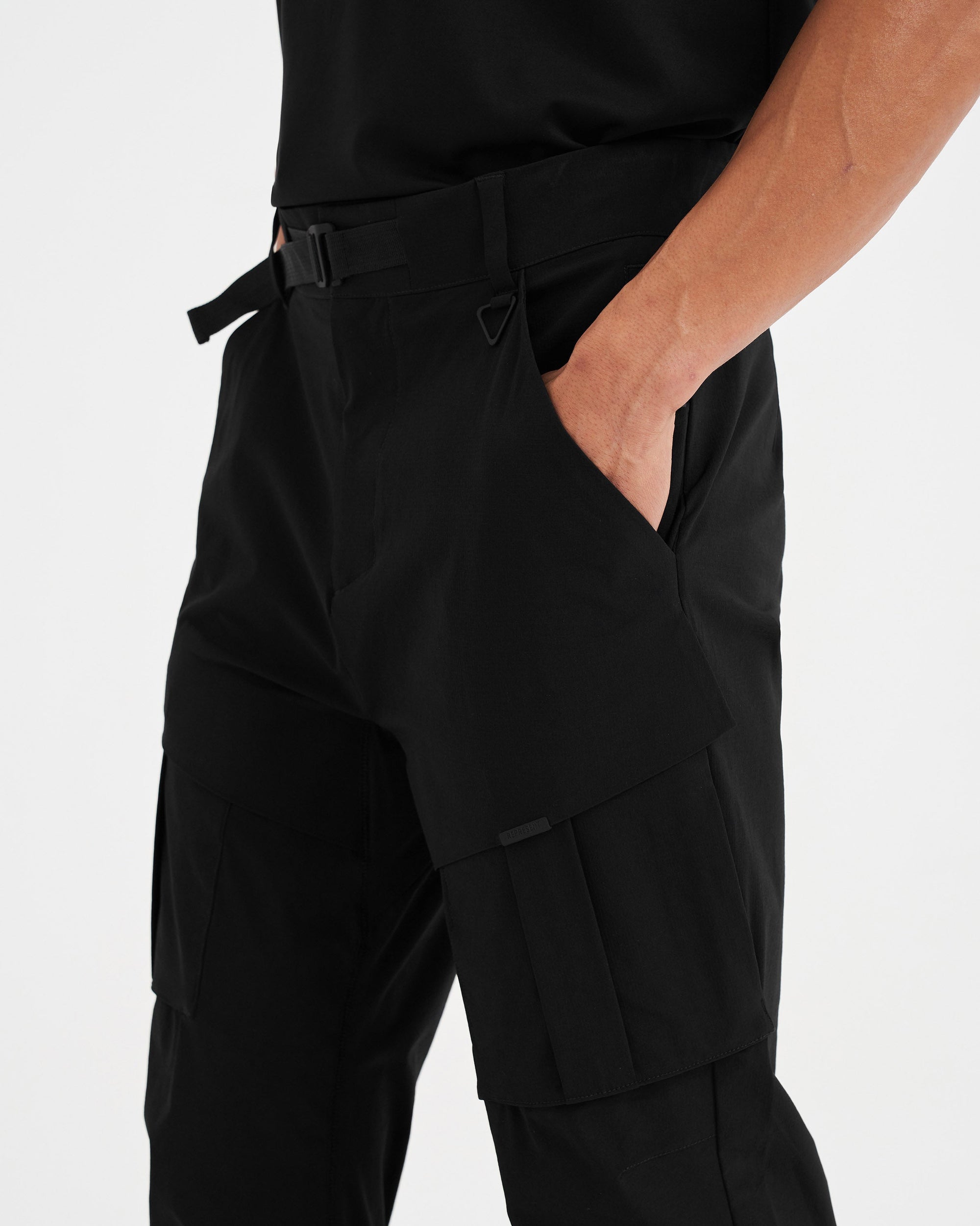 Man wearing a black cargo pant on a plain white background | 247 Hiking Pant in Black | Cargo style pant with tactical hardware and multiple pockets | 247 Pants | Represent Clo