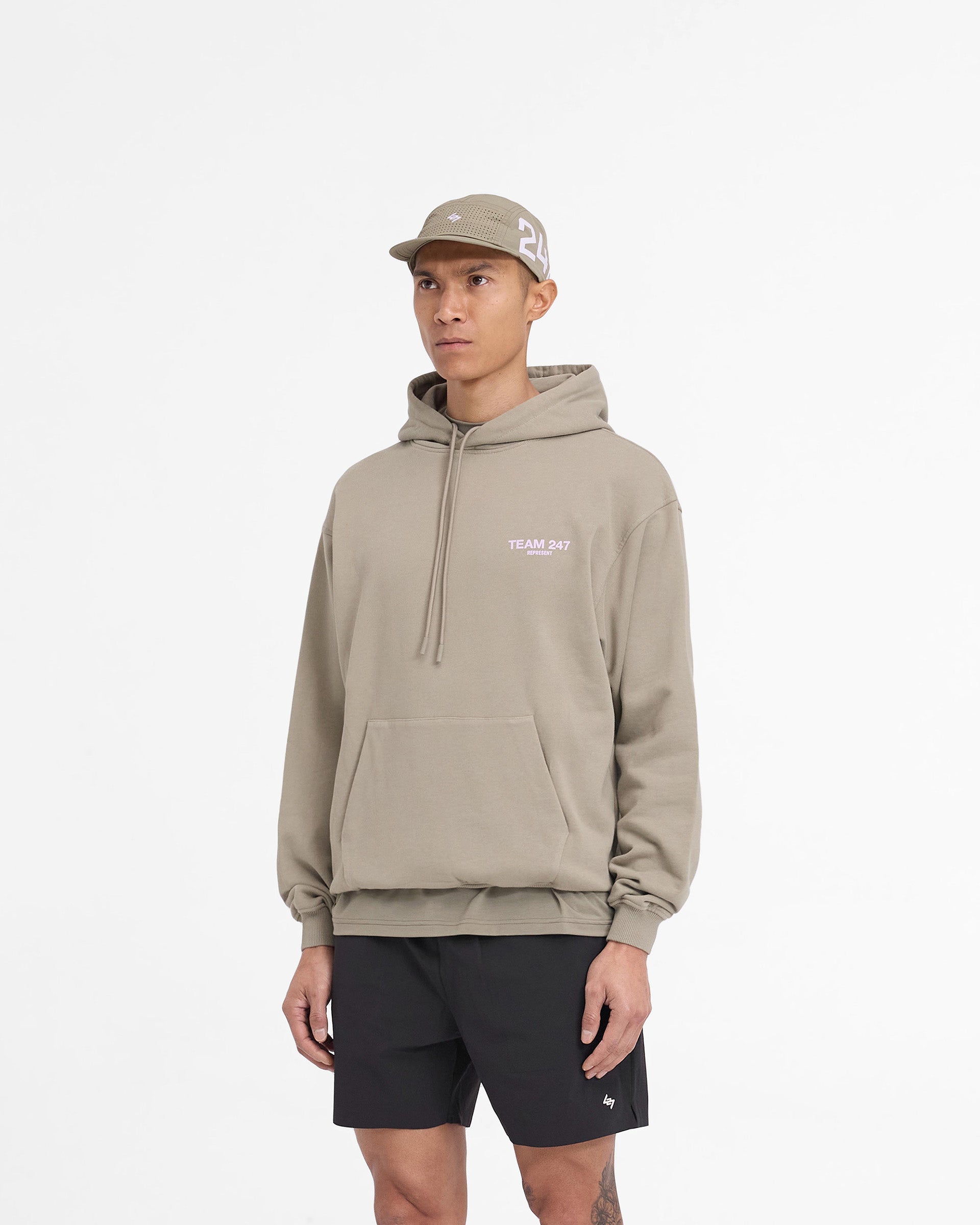 Man wearing a khaki hoodie with lilac accents on a plain white background | Team 247 Oversized Hoodie in Khaki Lilac | Oversized heavyweight cotton hoodie with Team 247 branding | 247 Hoodies | Represent Clo